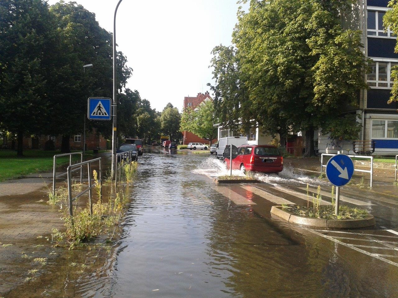 Ein Auto fährt über eine vom regen überflutete Straße in Alt-Laatzen.