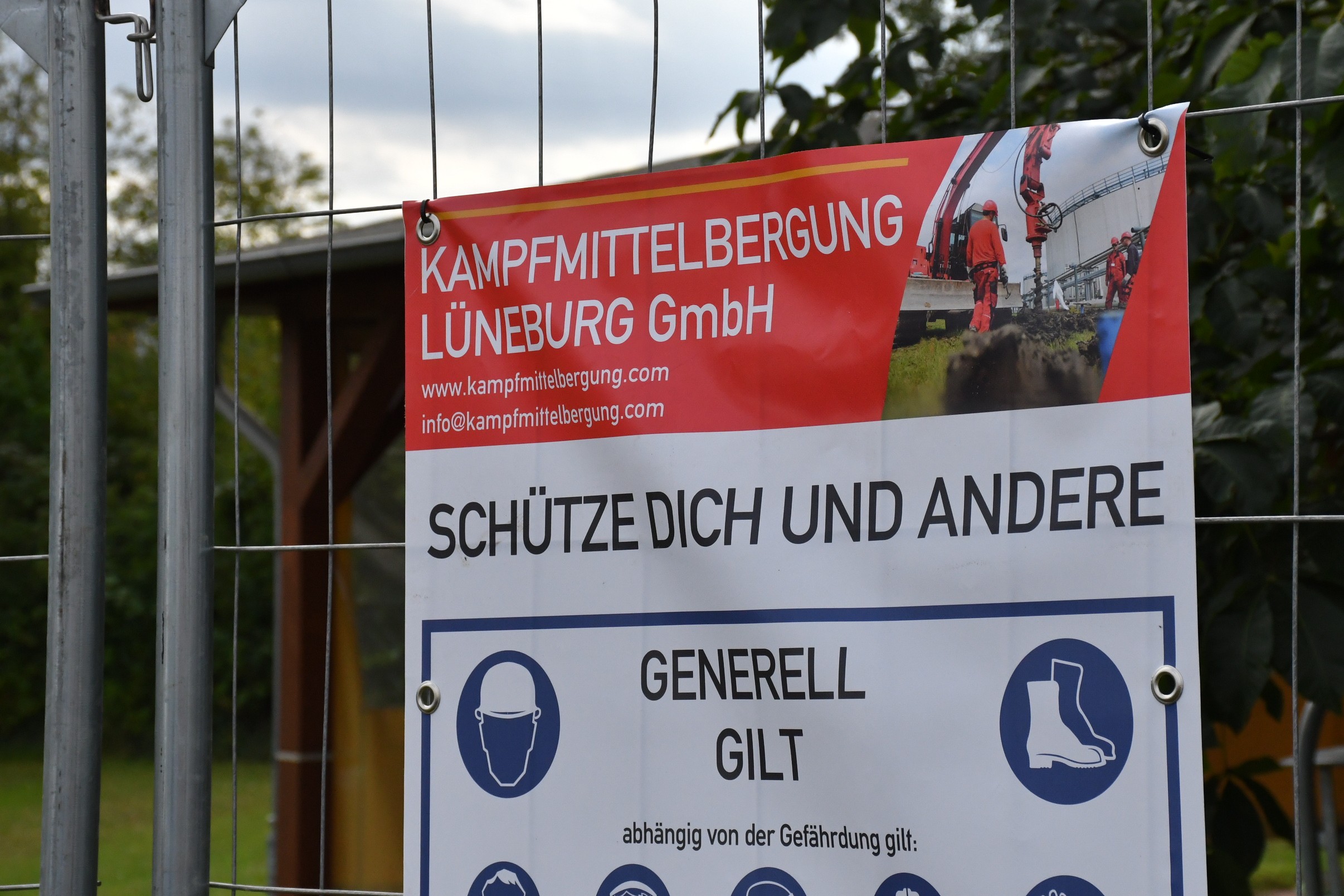 Nahaufnahme eines PVC-Banners an einem Bauzaun vor grüner Vegetation