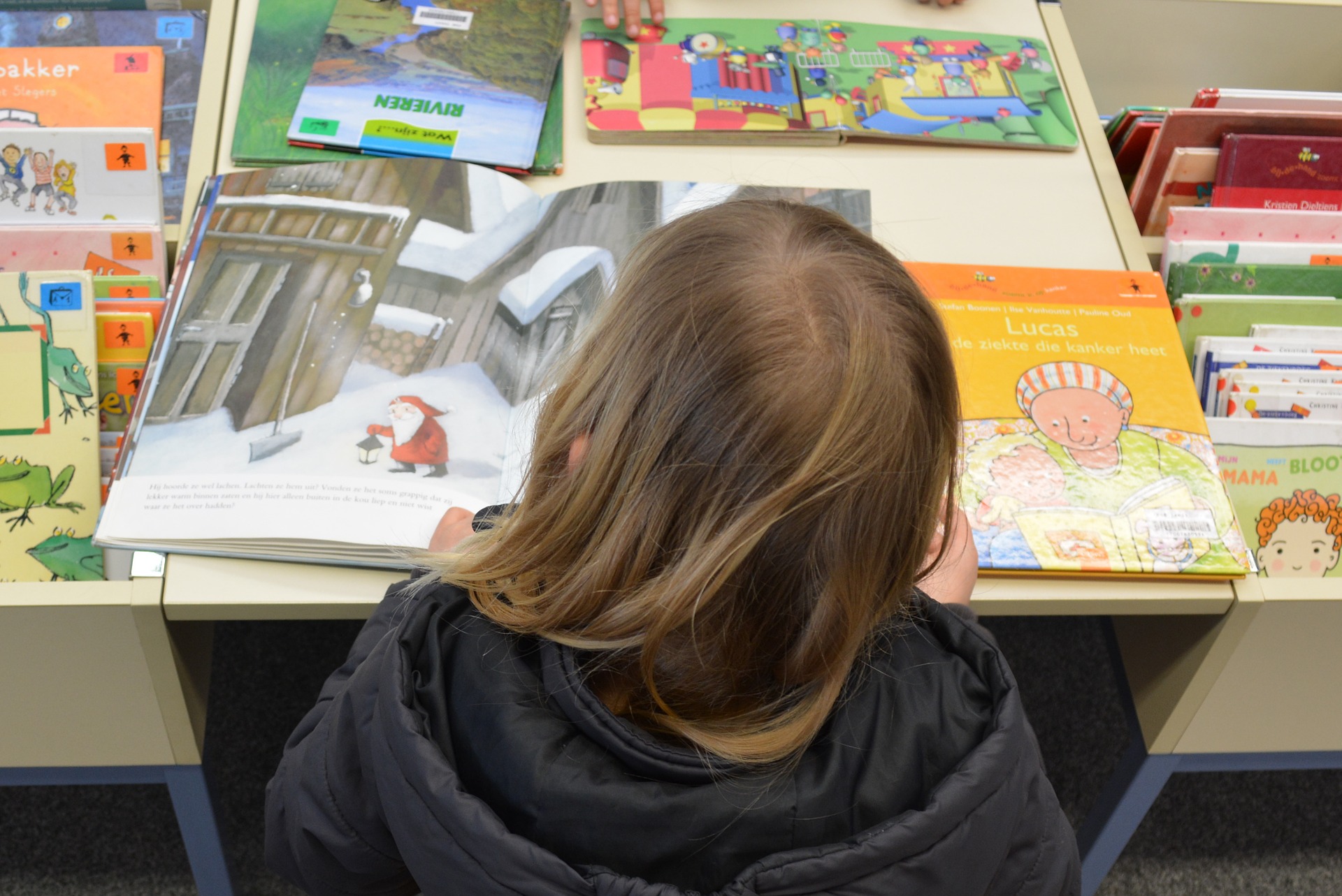 Mädchen von hinten fotografiert, schaut sich ein Buch an