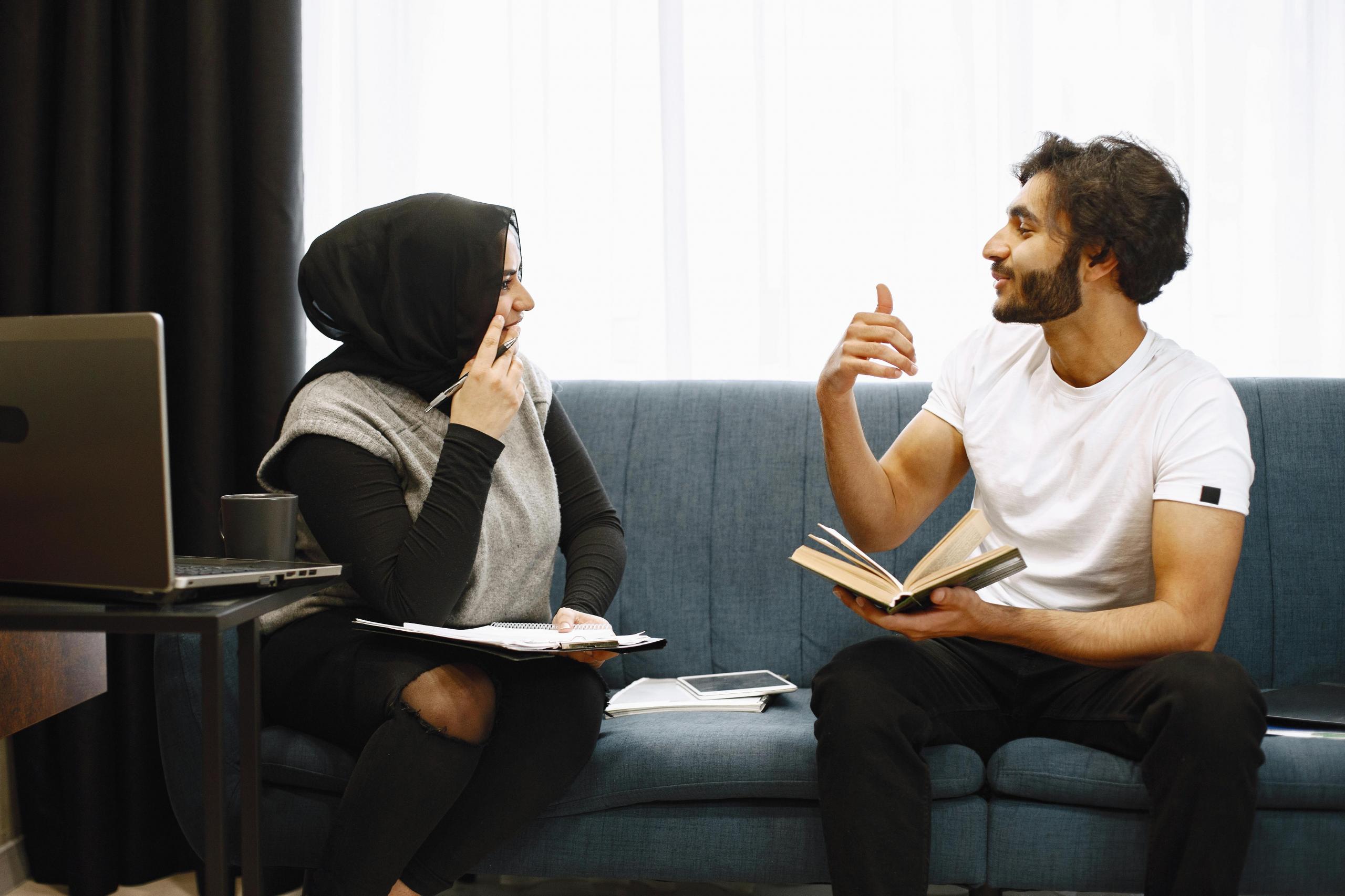 Eine Frau und ein Mann sitzen an einem Tisch und sprechen miteinander.