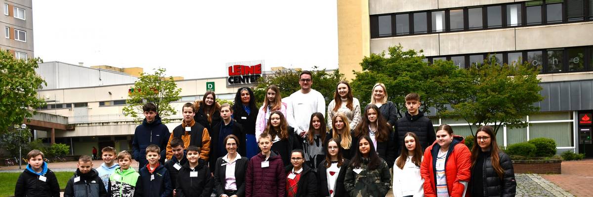 Eine Gruppe von Schülerinnen und Schülern stehen auf einem Brunnen. In ihrer Mitte steht der Bürgermeister Kai Eggert.