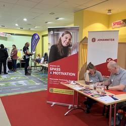 Messestand der Johanniter,, Gäste im Hintergrund