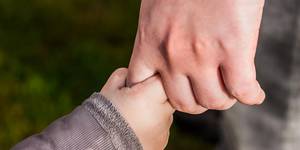 Kinderhand greift einen Finger eines erwachsenen Mannes
