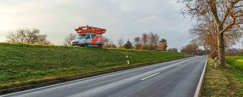 Ein Fahrzeug mit Kameras auf dem Autodach fährt auf einem höhergelegenen Weg.