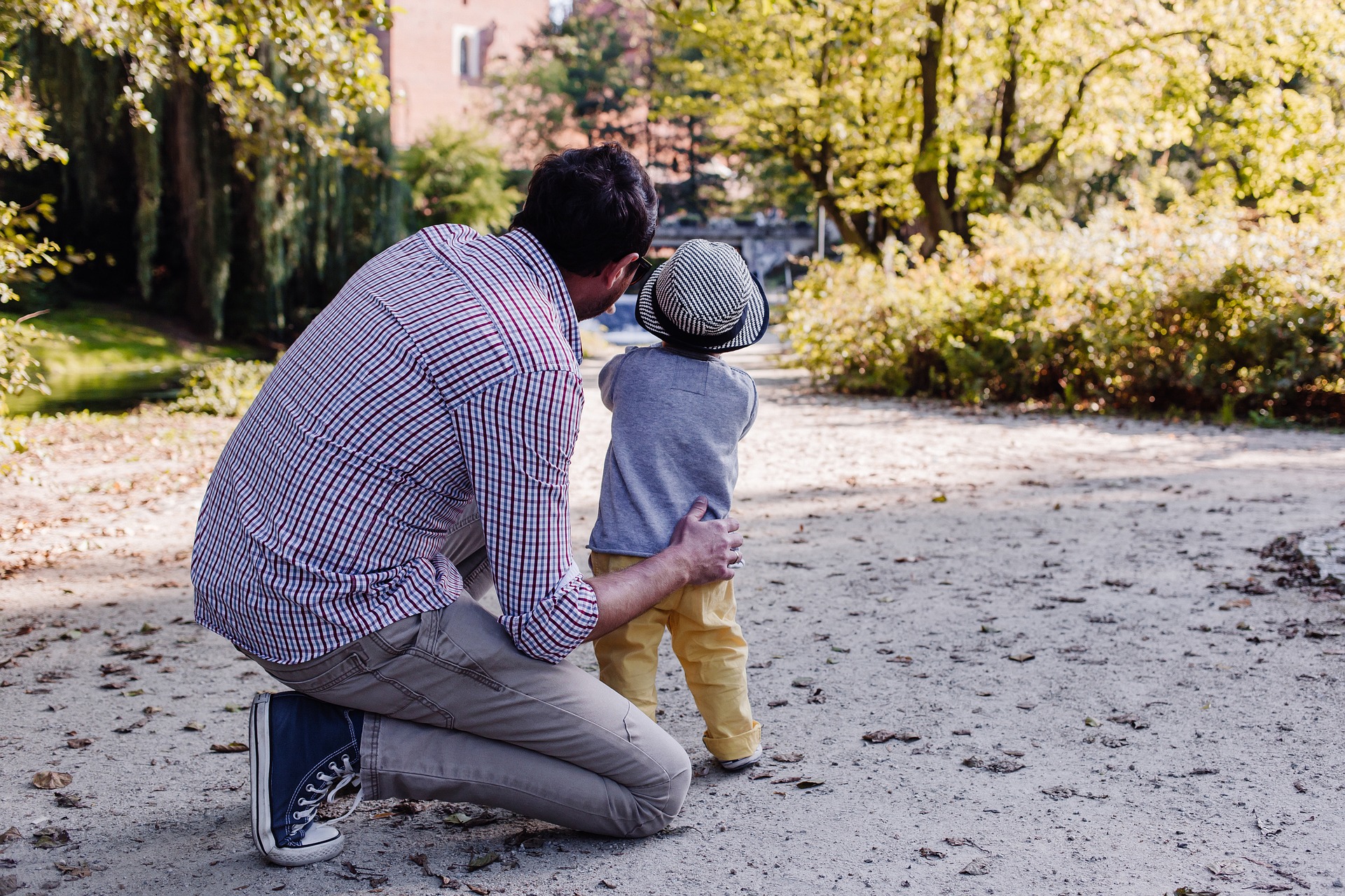 Vater kniet neben seinem Kind und spricht mit ihm