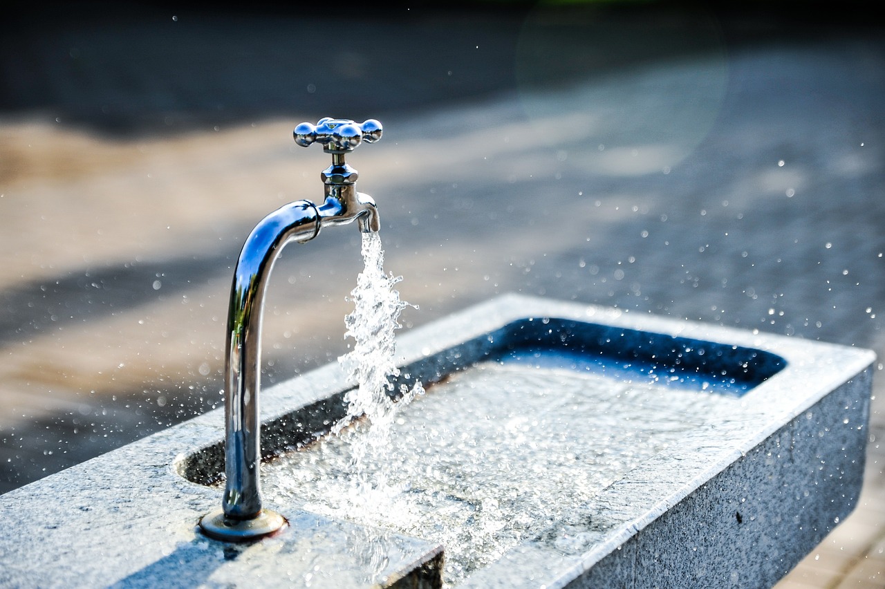 Wasser läuft aus einem Wasserhahn in ein Außenwaschbecken