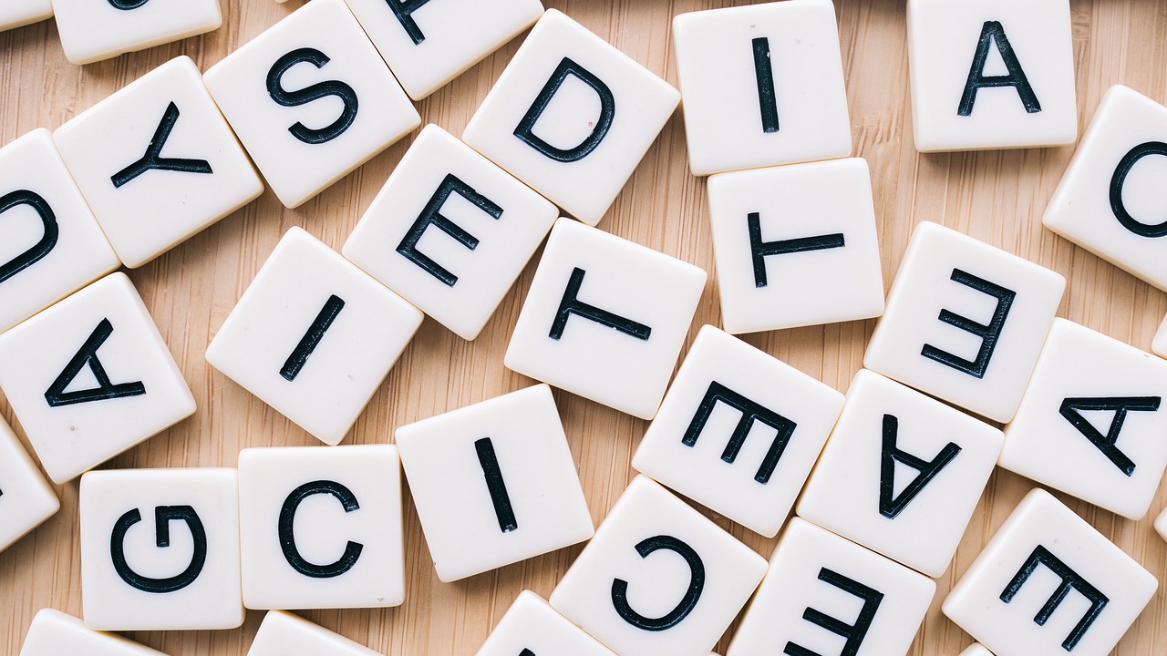 Buchstaben eines Scrabble-Spiels ungeordnet auf einem Tisch liegend