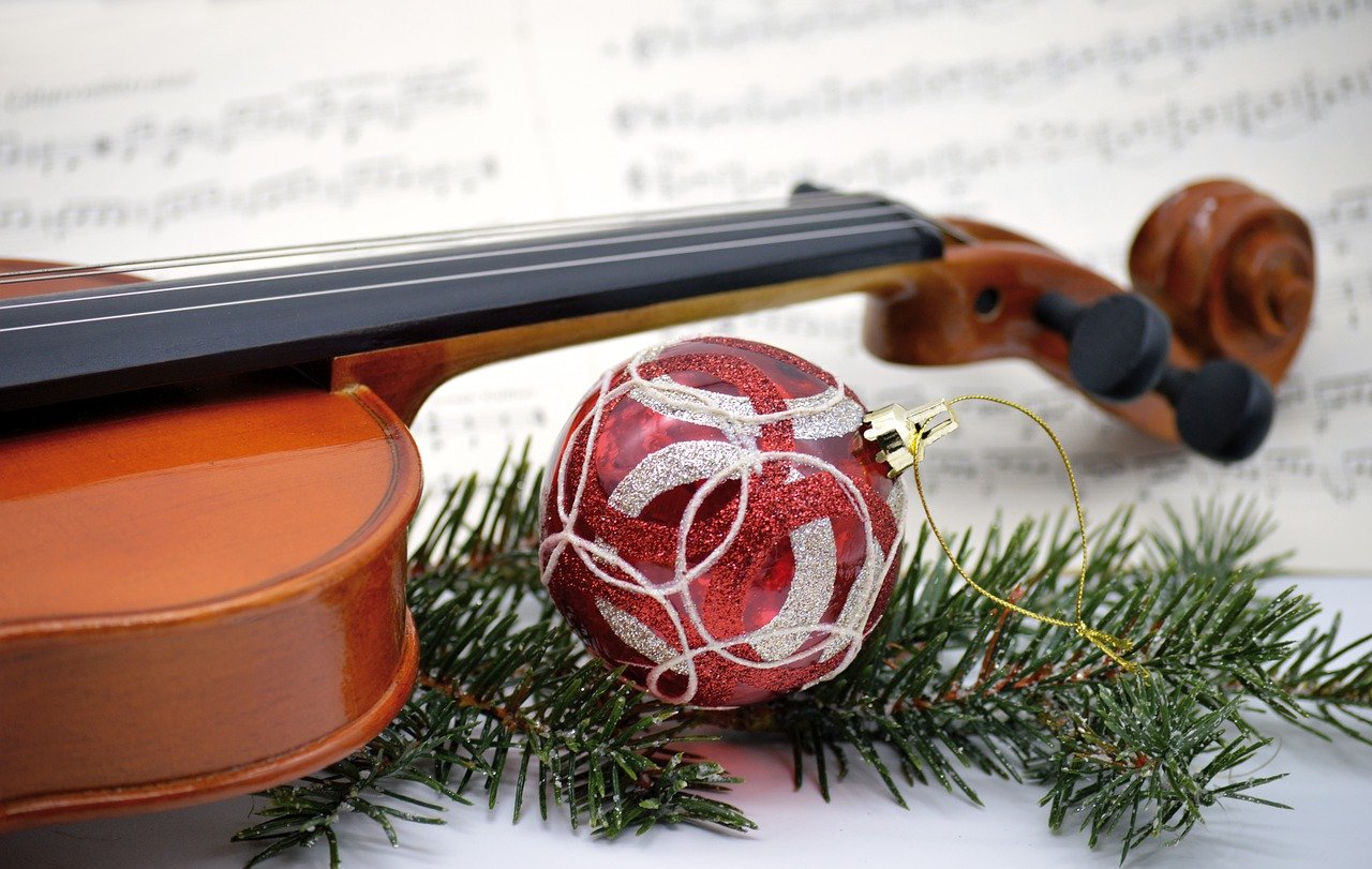 Eine rot weiße Weihnachtskugel und Tannenzweigen vor einer Violine