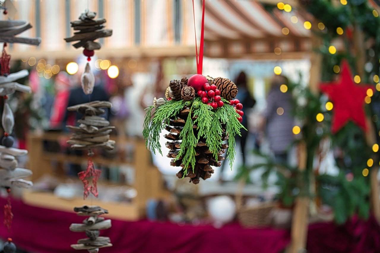 geschmückter Tannenzapfen in Nahaufnahme vor einem Weihnachtsmarktstand