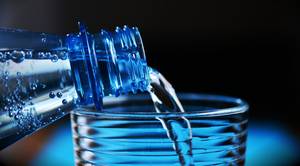 Wasser wird aus einer Trinkflasche in ein Glas gefüllt