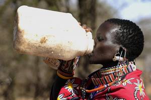 Eine schwarze Frau trinkt aus einem Wasserkanister.
