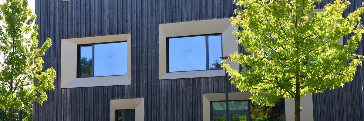 Holzhaus mit Treppen davor und grünen Bäumen.