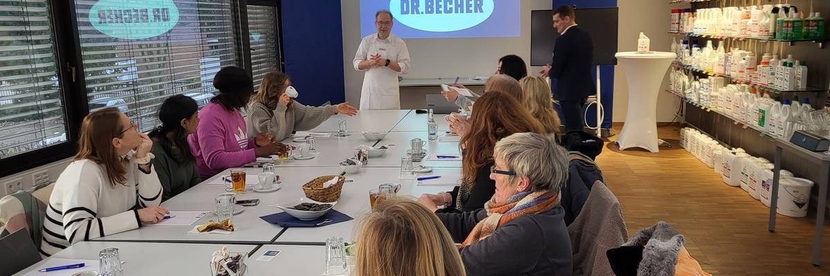 Der Dozent Herr Rempel präsentiert über einen Beamer eine HACCP Schulung. Die Küchenkräfte sitzen am Tisch mit dem Blick zum Beamer.