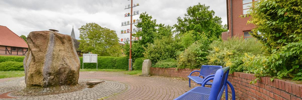 Platz im Frühling. Im Vordergrund steht eine blaue Bank.