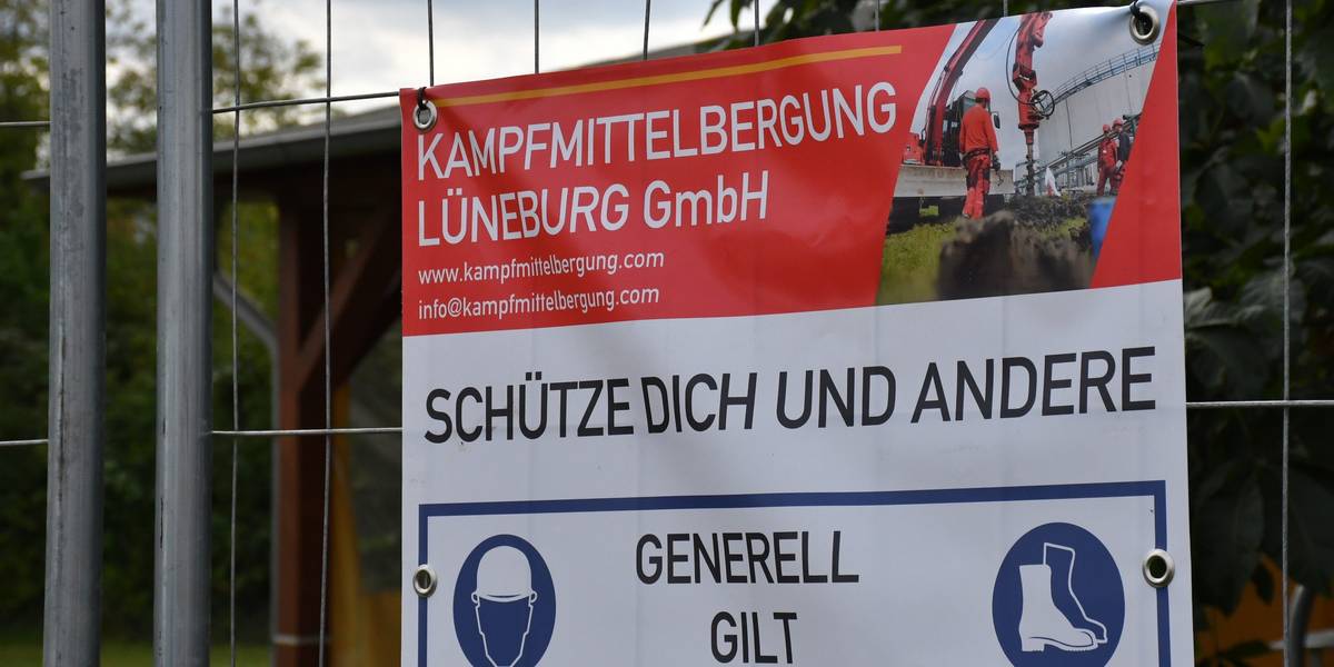 Nahaufnahme eines PVC-Banners an einem Bauzaun vor grüner Vegetation