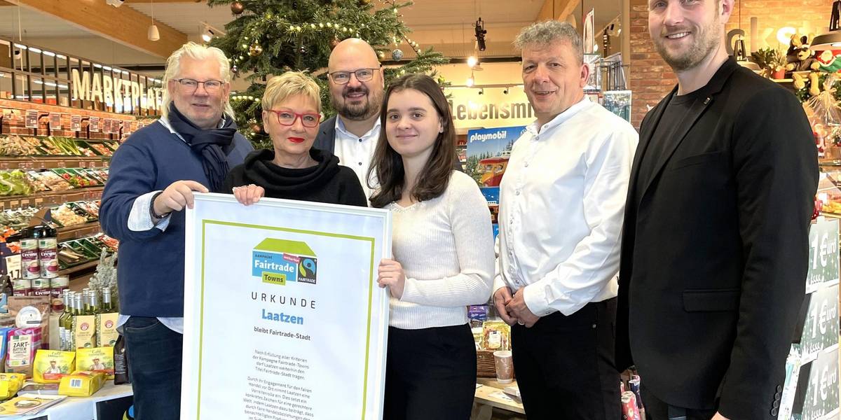 Eine Gruppe Personen steht vor einem Tannenbaum und einem Tisch mit Lebensmitteln