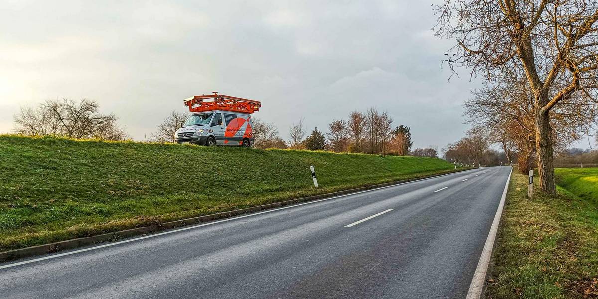 Ein Fahrzeug mit Kameras auf dem Autodach fährt auf einem höhergelegenen Weg.