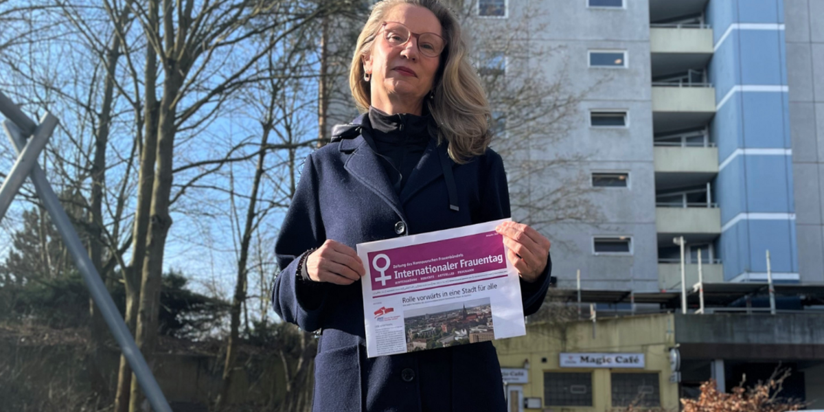 Eine Frau steht mit ernstem Blick hinter einem Kickertisch und vor einem Mehrfamilienhaus in Laatzen.