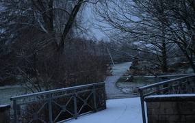 Brücke über die ein verschneiter Weg führt.