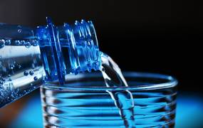 Wasser wird aus einer Trinkflasche in ein Glas gefüllt