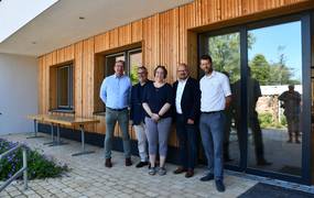 Fünf Menschen stehen vor einem Gebäude mit einer neuen Holzfassade.