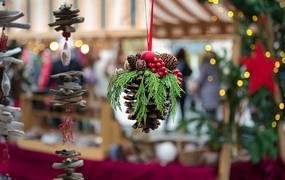 geschmückter Tannenzapfen in Nahaufnahme vor einem Weihnachtsmarktstand