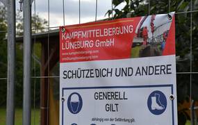 Nahaufnahme eines PVC-Banners an einem Bauzaun vor grüner Vegetation