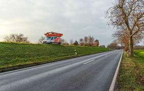 Ein Fahrzeug mit Kameras auf dem Autodach fährt auf einem höhergelegenen Weg.