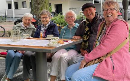 Eine Gruppe von Personen sitzen an einem Tisch im Park.