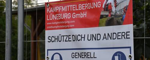 Nahaufnahme eines PVC-Banners an einem Bauzaun vor grüner Vegetation