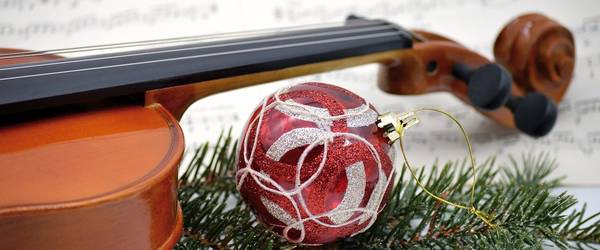 Eine rot weiße Weihnachtskugel und Tannenzweigen vor einer Violine