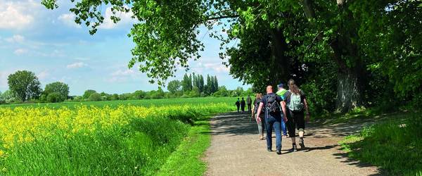 Der Bürgermeister und Bürgerinnen und Bürger wandern über einen Feldweg