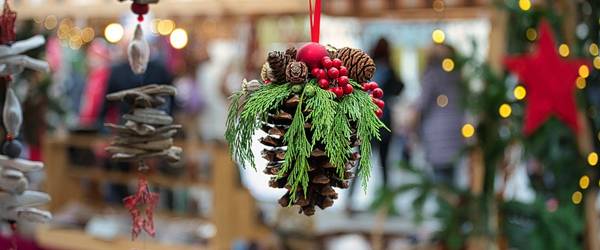 geschmückter Tannenzapfen in Nahaufnahme vor einem Weihnachtsmarktstand